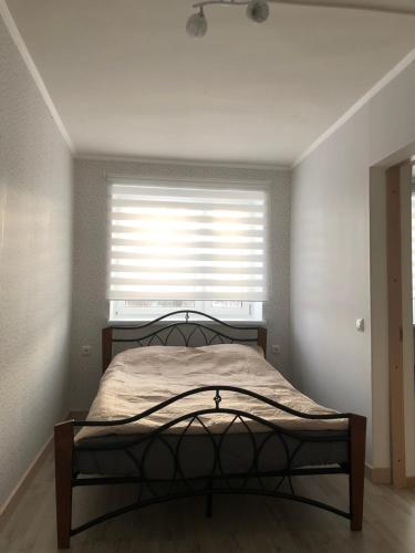 Schlafzimmer mit einem Bett und einem Fenster mit Jalousien in der Unterkunft Soelaane 12 Apartments in MikitamÃ¤e