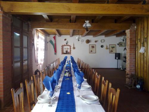 a long table with blue napkins and chairs in a room at Kéktó Kemping in Gyékényes