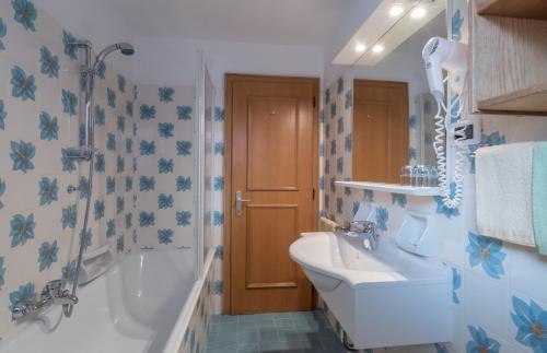 a bathroom with a tub and a sink and a shower at Garni La Vara in Corvara in Badia