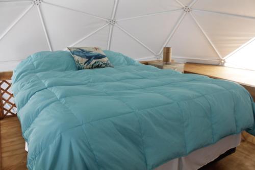 a large blue bed in a tent at Kunza Kamanchacos in Punta de Choros