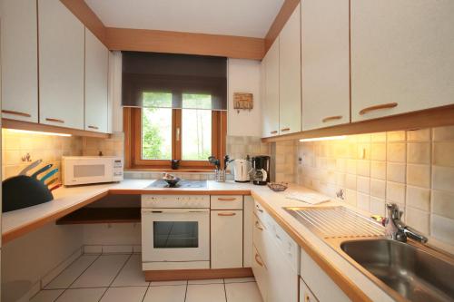 a kitchen with white cabinets and a sink at Edelweiss am See in Zell am See