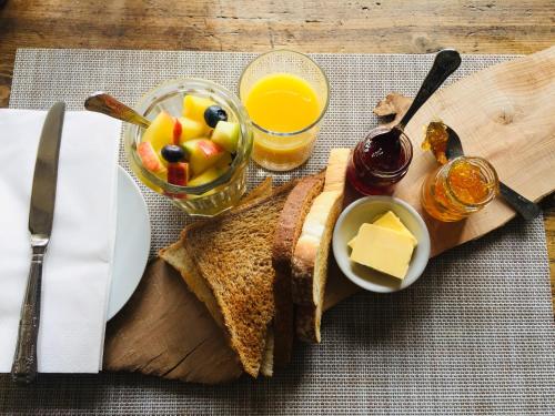 a plate of food with toast and a bowl of fruit and juice at The Bridge House in Bridport