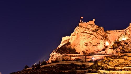 a castle on top of a mountain at night at SohoSuites Villavieja in Alicante