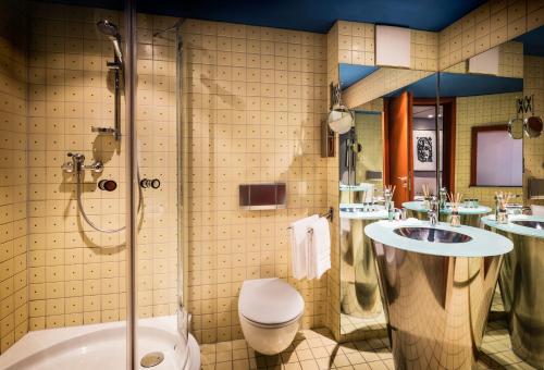 a bathroom with two sinks and a toilet and a shower at Penck Hotel Dresden in Dresden