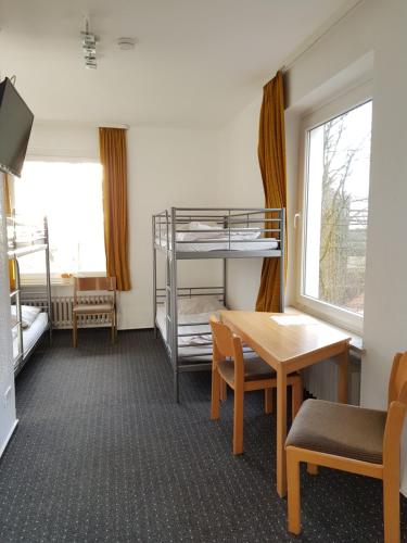 a room with a table and a bunk bed at Berghotel in Bad Oeynhausen
