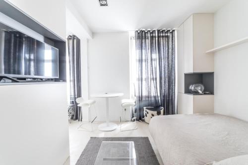 une chambre blanche avec un lit et une table dans l'établissement Studio design Nuée bleue tout équipé centre ville, à Strasbourg