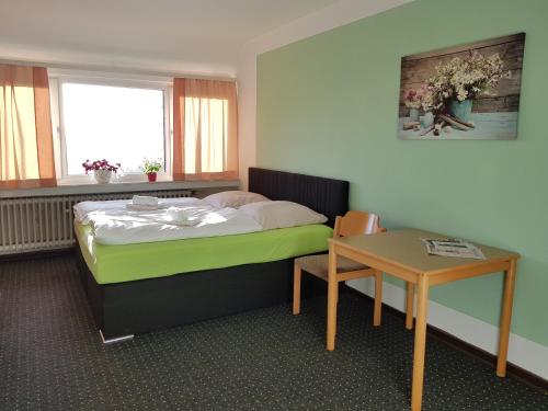a bedroom with a bed and a table and a window at Berghotel in Bad Oeynhausen