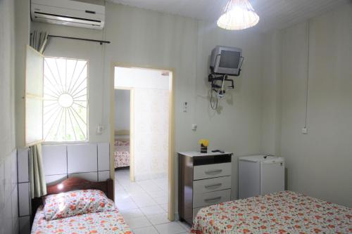 um quarto com uma cama e uma televisão na parede em Pousada Belo Mar em Maceió