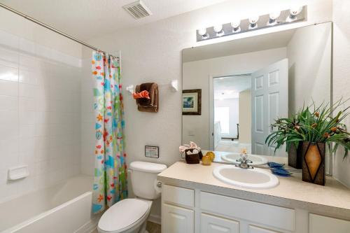 a bathroom with a sink and a toilet and a mirror at Olivia's Dream Villa on WindsorHills in Orlando
