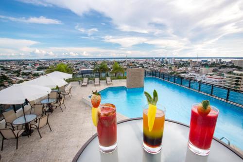 a table with drinks on a balcony with a pool at Intercity Manaus in Manaus