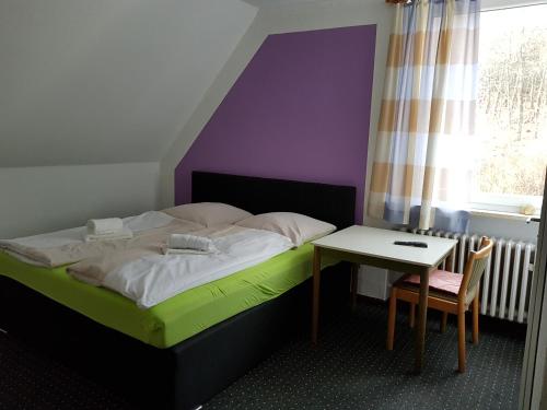 a bedroom with a bed and a table and a window at Berghotel in Bad Oeynhausen