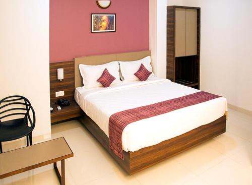a bedroom with a bed and a table and a chair at Hotel Nirvana in Alibaug