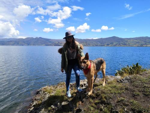 a woman and her dog standing on the edge of a lake at La cabaña de sol in Aquitania