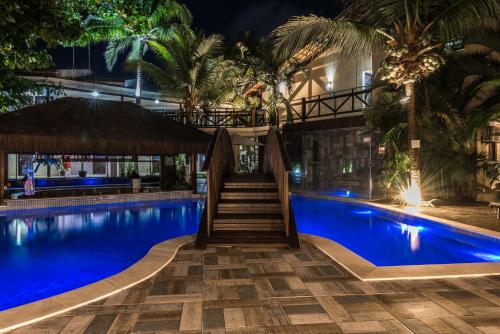 a hotel swimming pool with a staircase leading to a building at Pousada Recanto do Lobo in Porto De Galinhas