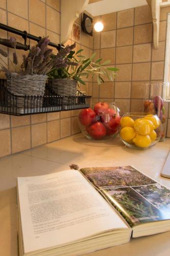 a book on a counter with a bowl of fruit at Le Gioie - Villa Macchia Mediterranea - Splendida villa vista mare immersa nel verde in Torre Pali 