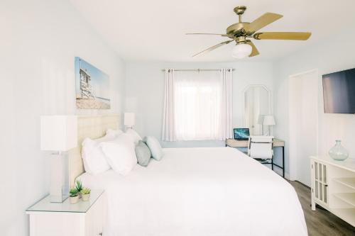 a white bedroom with a white bed and a ceiling fan at Bayside Hotel in Los Angeles