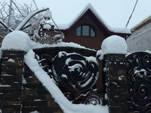 a stone fence covered in snow in front of a house at У Гуцула in Mukacheve