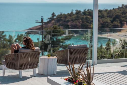 a woman sitting in a chair looking at the ocean at 360ᵒ Luxury View Collection - Adults Only in Limenaria