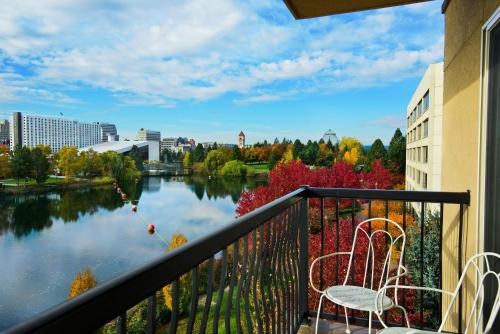 a balcony with two chairs and a view of a river at Oxford Suites Spokane Downtown in Spokane