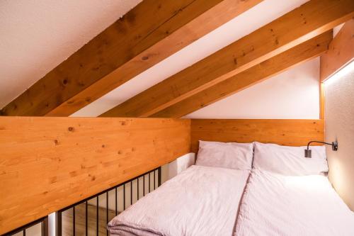 a bed in a room with wooden ceilings at Hotel Folgarida in Folgarida