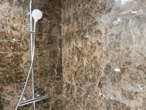 una doccia in un bagno con un muro in pietra di Ripple - Modern Condo with pool, aircon, parking a Lisbona