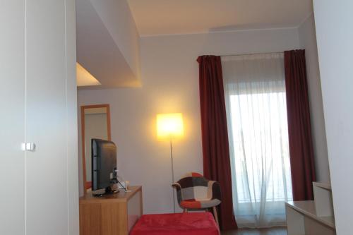 a hotel room with a television and a red chair at Hotel La Sosta in Cisano Bergamasco