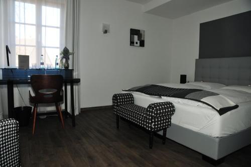a bedroom with a bed and a desk and a chair at Hotel Sporcher Nest in Cadolzburg