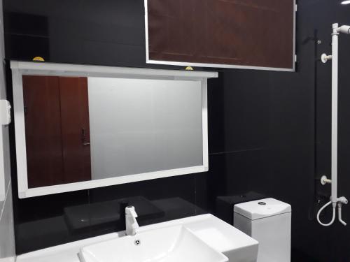 a bathroom with a sink and a mirror and a toilet at Brinthavanam Days Inn in Jaffna
