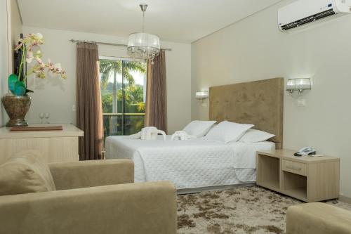 a white bedroom with a bed and two chairs at Marruá Hotel in Bonito