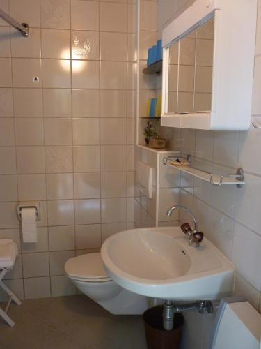 a white bathroom with a toilet and a sink at Landhaus Monika in Bodensdorf