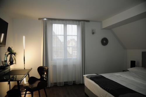 a bedroom with a bed and a desk and a window at Hotel Sporcher Nest in Cadolzburg