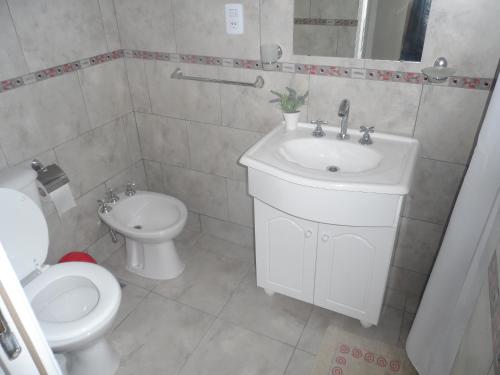 a white bathroom with a toilet and a sink at La soleada in San Clemente del Tuyú