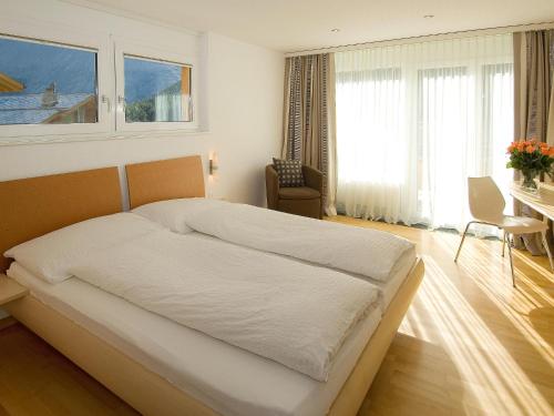 una camera da letto con un grande letto bianco, una scrivania e una finestra di Dolce Vita a Saas-Fee