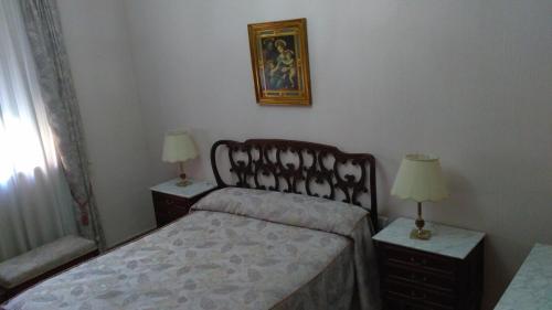 a bedroom with a bed and two night stands with lamps at Casa Nicolás in Ávila
