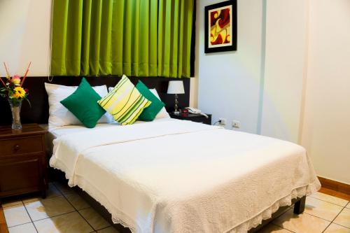 a bedroom with a large white bed with green curtains at Hotel Fatima Inn in Tarapoto
