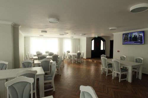 uma sala de jantar com mesas e cadeiras brancas em Pensiunea Hanna em Baile Felix