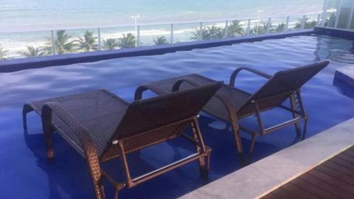two wicker chairs sitting next to a swimming pool at Flat Mar Bello Plaza in Cabedelo