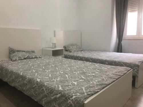 a bedroom with two beds and a window at Chainha's Dream Apartment in Sesimbra