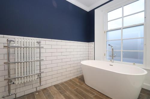 a bathroom with a white tub and a window at Dollar Apartments-41 Bridge Street in Dollar