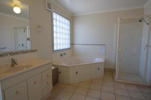 a bathroom with a tub and a sink and a shower at City Centre Motel in Bendigo