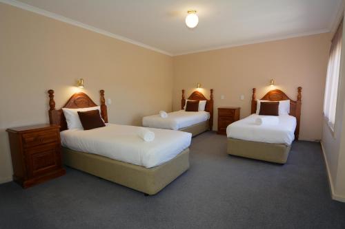 a hotel room with two beds and two ottomans at City Centre Motel in Bendigo