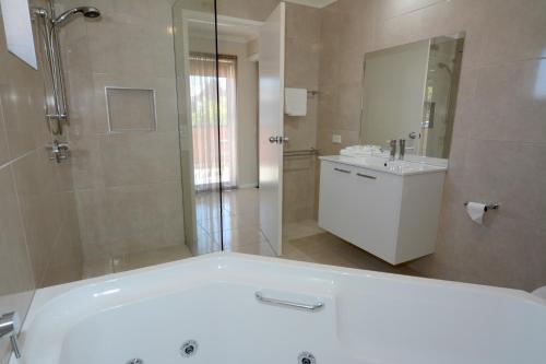 a bathroom with a tub and a shower and a sink at City Centre Motel in Bendigo