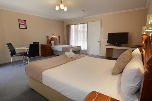 a hotel room with two beds and a table and a television at City Centre Motel in Bendigo