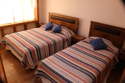 a bedroom with two beds with blue pillows at Hostal Luna del Mar 840-B in La Serena