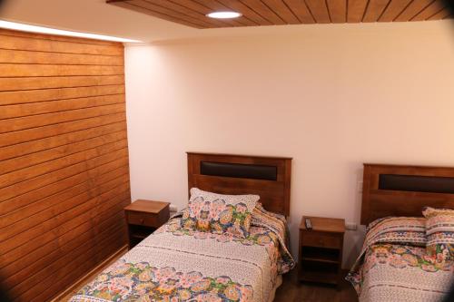 a bedroom with two beds and wooden walls at Hostal Luna del Mar 840-B in La Serena