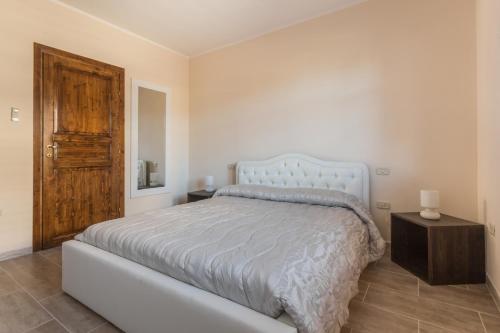 a white bedroom with a bed and a wooden door at Anaelehouserooms LTB in Arborea 