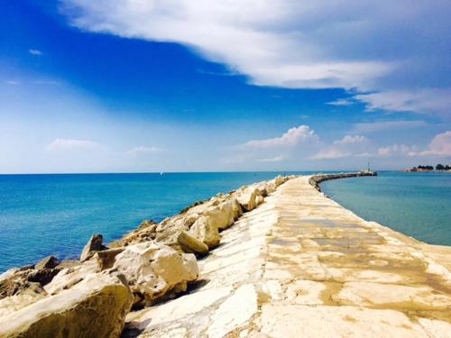 a stone pathway leading into the ocean with a blue sky at Apartment Umag Nelly in Umag