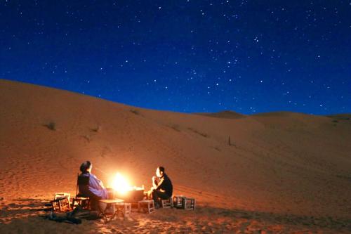 two people sitting around a fire in the desert at Overnight Desert Camp in Merzouga