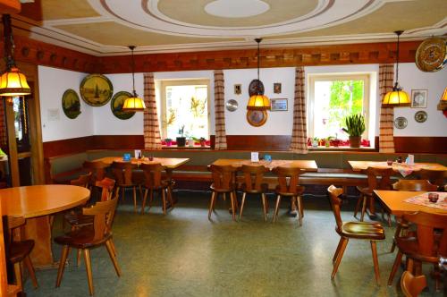 ein Restaurant mit Holztischen, Stühlen und Fenstern in der Unterkunft Bayersoier Hof in Bayersoien