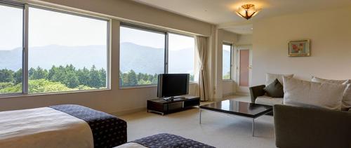 a bedroom with a bed and a couch and a tv at Kagetsuen in Hakone